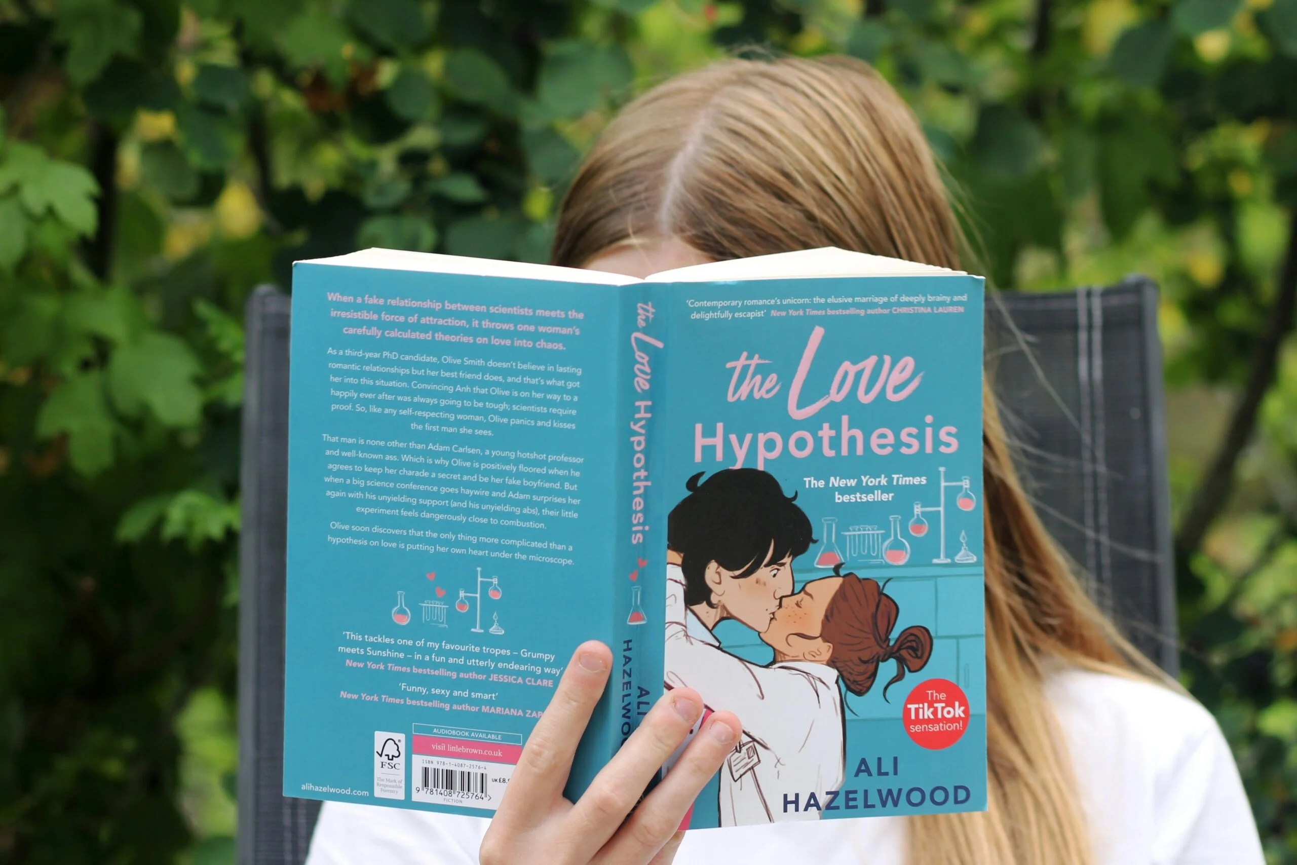 a girl reading a book about the love of hypothesis booktok